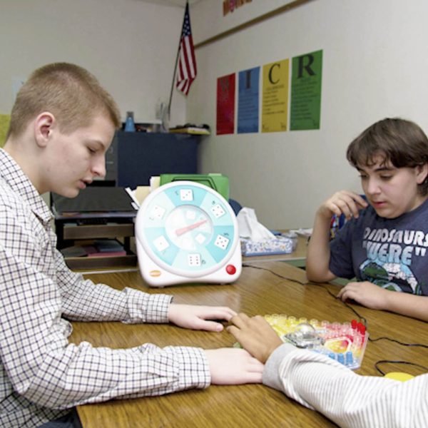 Two young adults using the All-Turn-It spinner to play a board game