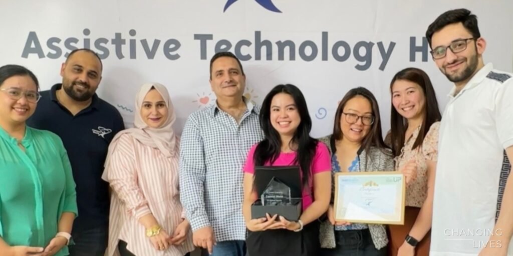 The Consort World team holding the Tobii Dynavox Brand Champion award in front of the Assistive Technology Hub banner