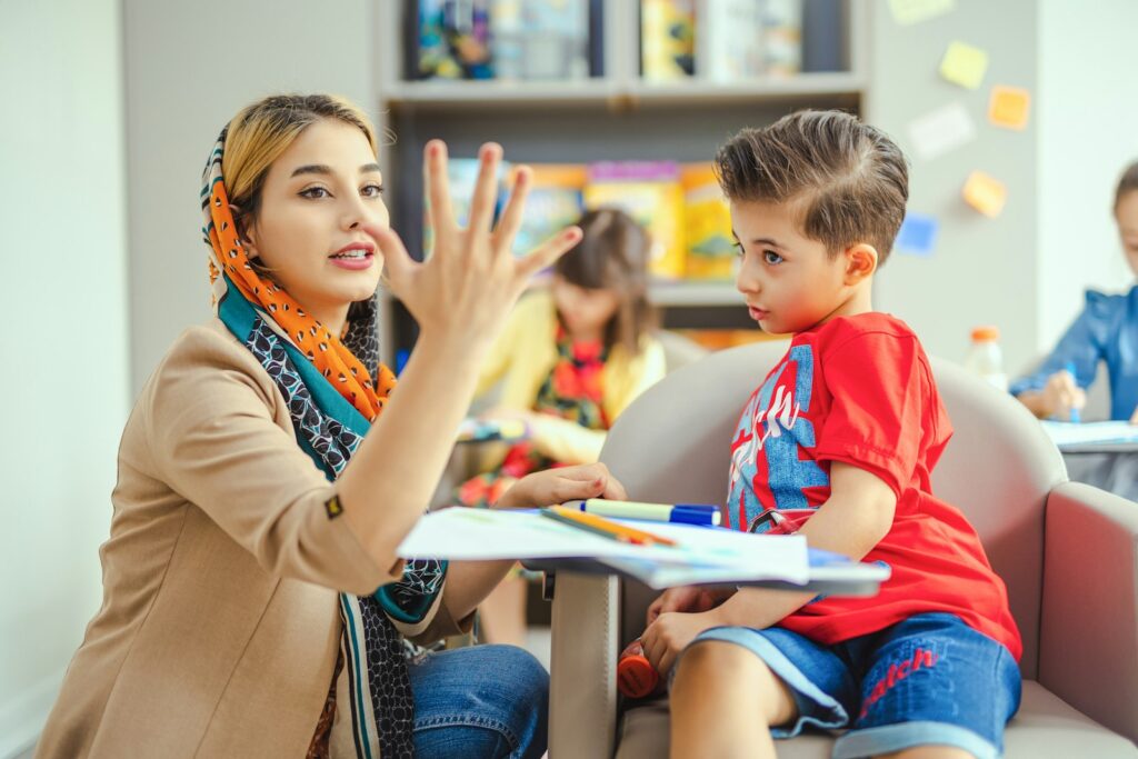 A teacher talking with a young boy at a table