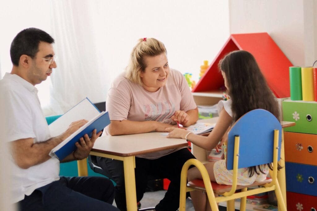 A therapist working with a child and her parents at a table
